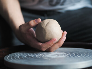 Ceramist young woman preparing clay to make pottery pieces in her studio; anonymous hands at work....