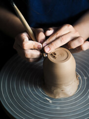 Ceramist at work using tools for creating handmade vase in studio, selective focus. Close up of...