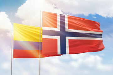 Sunny blue sky and flags of norway and colombia