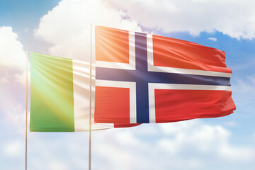 Sunny blue sky and flags of norway and italy