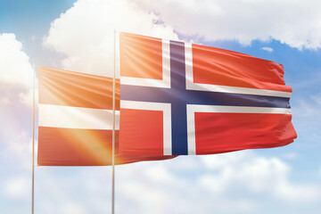 Sunny blue sky and flags of norway and latvia