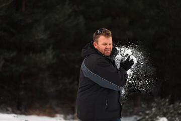 Adult man playing in winter snow ball fight