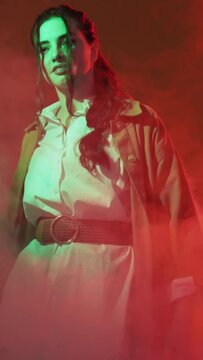 Color light people. Synthwave trend. 80s sci-fi. Pretty cyberpunk style woman in creative smoke flow bright neon glow on red background vertical.