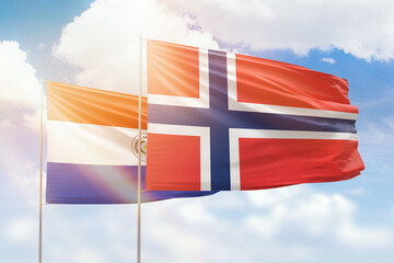 Sunny blue sky and flags of norway and paraguay