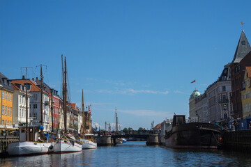 Obraz premium Nyhavn is a waterfront and canal in Copenhagen, Denmark. Colourful facades of houses and old ships along the canal. Wooden ships moored in the canal