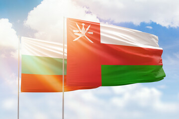 Sunny blue sky and flags of oman and bulgaria