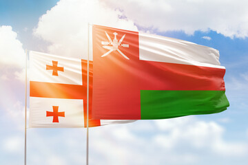 Sunny blue sky and flags of oman and georgia