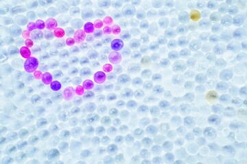 たくさんの半透明な球状のシリカゲルと赤く着色したシリカで左上に並べたハート型