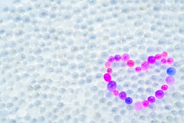 丸い粒状の脱水剤のシリカゲルで作った赤と紫の可愛らしいハートマーク