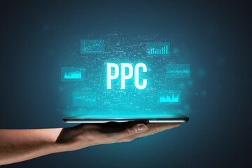 Concept PPC or Pay per click. Business acronym. Holographic icons and text over tablet in hands