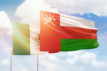 Sunny blue sky and flags of oman and mexico