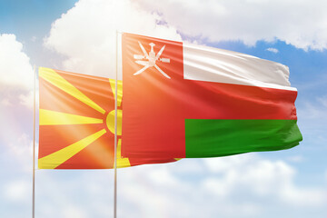 Sunny blue sky and flags of oman and north macedonia