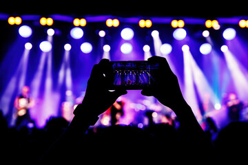 Fototapeta na wymiar Holding a smartphone to record music concert. Mobile phone at a summer festival.