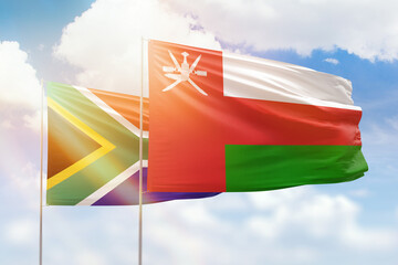 Sunny blue sky and flags of oman and south africa