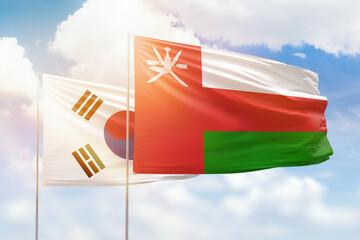 Sunny blue sky and flags of oman and south korea