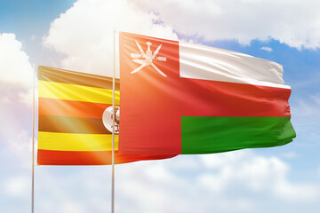 Sunny blue sky and flags of oman and uganda