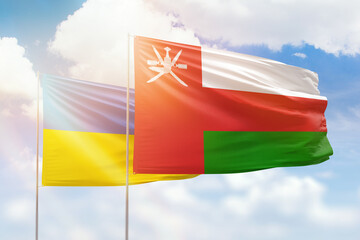 Sunny blue sky and flags of oman and ukraine