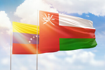 Sunny blue sky and flags of oman and venezuela