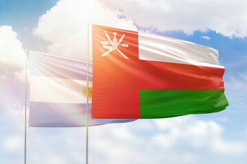 Sunny blue sky and flags of oman and argentina