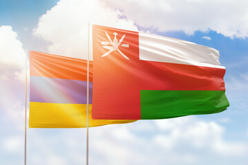 Sunny blue sky and flags of oman and armenia