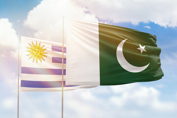 Sunny blue sky and flags of pakistan and uruguay