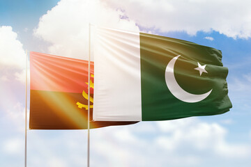 Sunny blue sky and flags of pakistan and angola