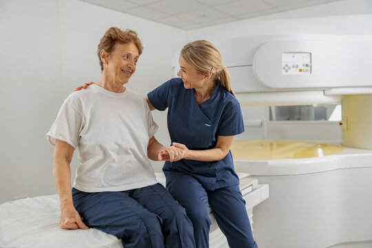 Radiologist help to patient sit after procedure of MRI or CT Scan . High Tech medical equipment