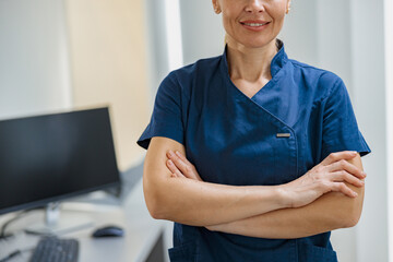 Close up of doctor in uniform standing with crossing hands in clinic. High quality photo