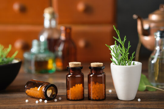 Bottles of homeopathic granules, cabinet with homeopathic remedies and tincture bottles on background. Homeopathy medicine concept.