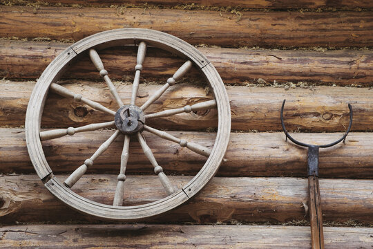Old wooden wheel and retro oven fork on wooden wall. © chamillew