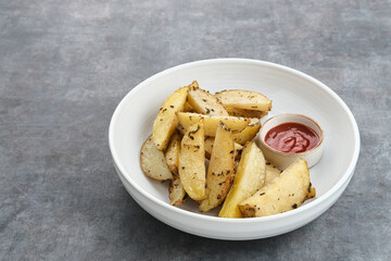 Roasted potato wedges with rosemary and herbs, served with chili sauce
