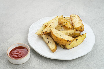 Roasted potato wedges with rosemary and herbs, served with chili sauce
