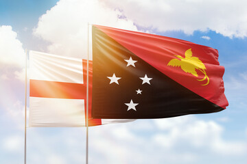 Sunny blue sky and flags of papua new guinea and england