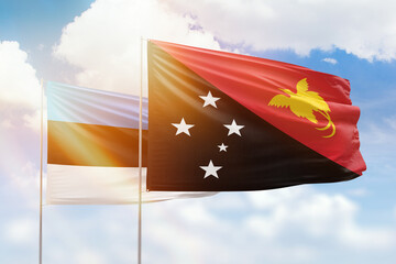 Sunny blue sky and flags of papua new guinea and estonia