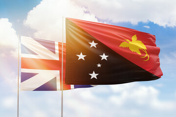 Sunny blue sky and flags of papua new guinea and great britain