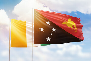 Sunny blue sky and flags of papua new guinea and ivory coast