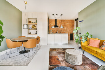A bright sofa with soft cushions, pouffes of different colors arranged on a carpet, a round wooden...