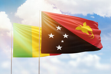 Sunny blue sky and flags of papua new guinea and mali