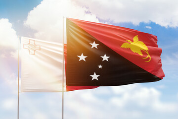 Sunny blue sky and flags of papua new guinea and malta