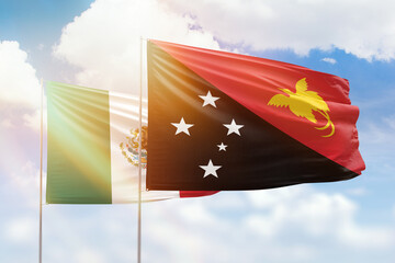 Sunny blue sky and flags of papua new guinea and mexico