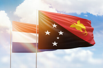 Sunny blue sky and flags of papua new guinea and netherlands