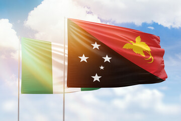 Sunny blue sky and flags of papua new guinea and nigeria