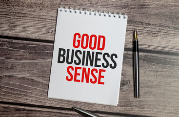 notebook with the word GOOD BUSINESS SENSE on wooden background