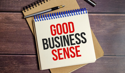 notebook with the word GOOD BUSINESS SENSE on wooden background