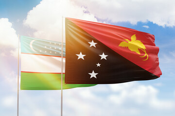 Sunny blue sky and flags of papua new guinea and uzbekistan