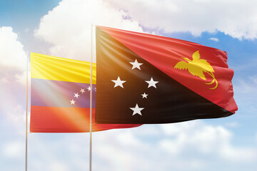 Sunny blue sky and flags of papua new guinea and venezuela