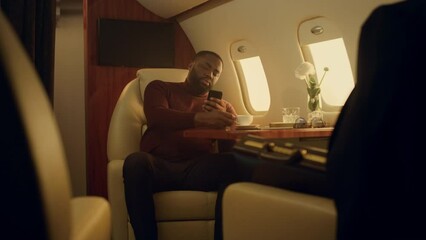 Happy man browsing internet in first class. Cheerful passenger drinking coffee
