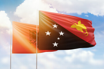 Sunny blue sky and flags of papua new guinea and albania