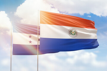 Sunny blue sky and flags of paraguay and honduras