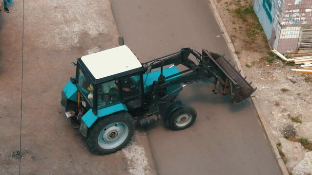 Tractor dumps construction debris into the truck. The garbage truck is working hard. Garbage collection near garbage cans.